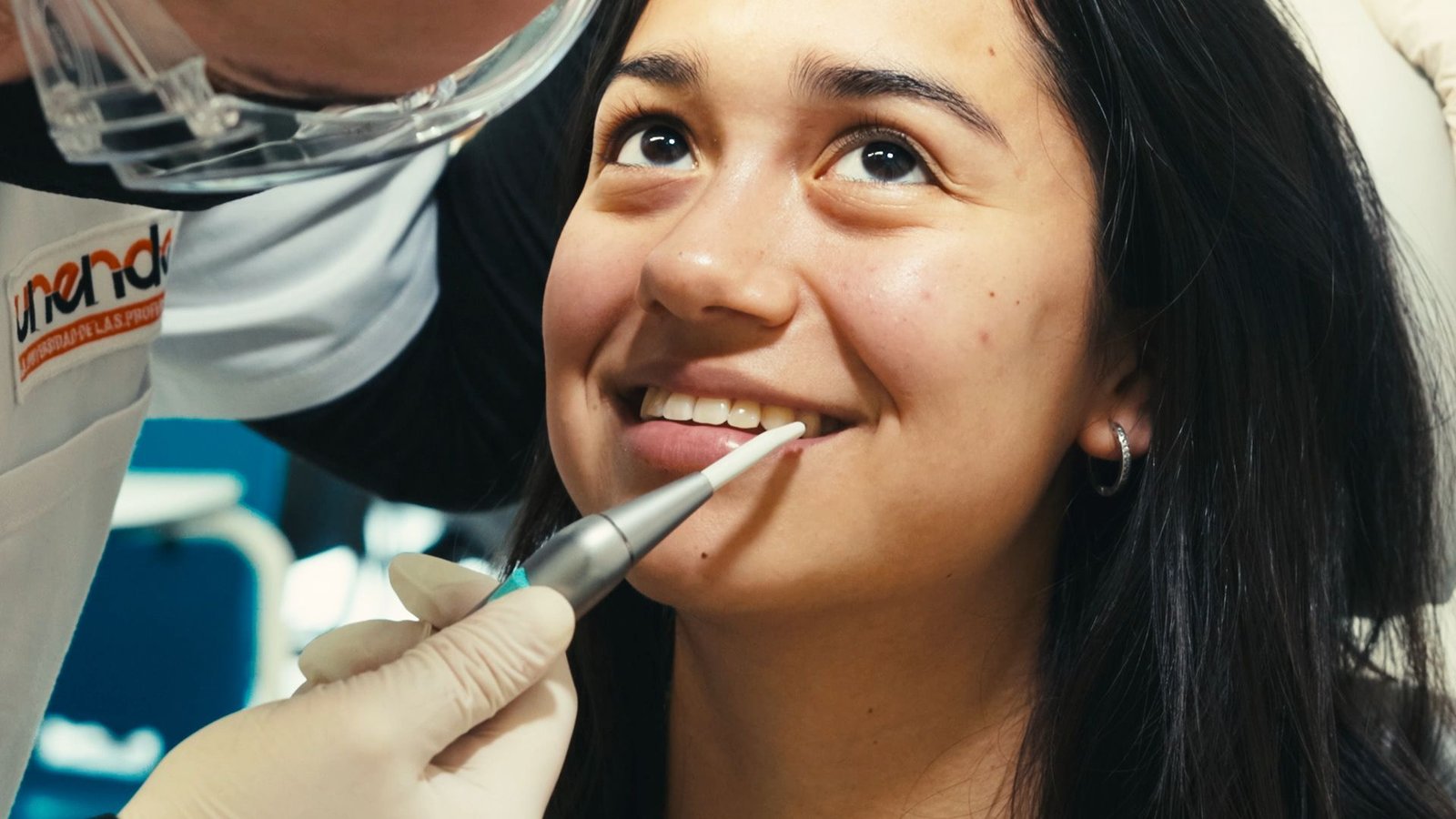 Primer plano de una alumna sonriente mientras le acercan un instrumento a la boca.